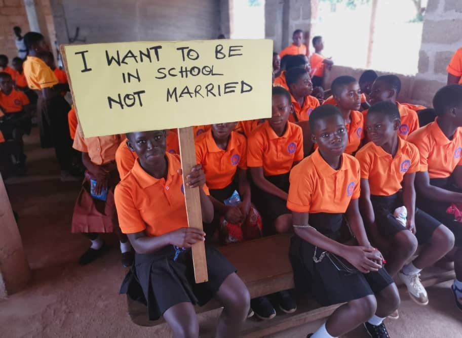 Girls holding sign: "I want to be in school, not married"